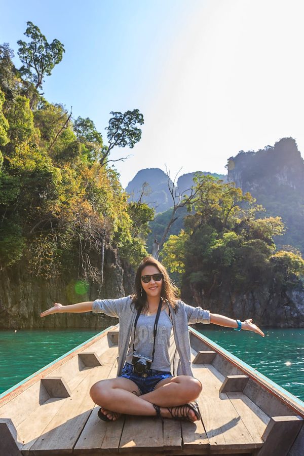 Asian woman relishing a serene boat journey through the lush karst landscape of Thailand's Khlong Sok.