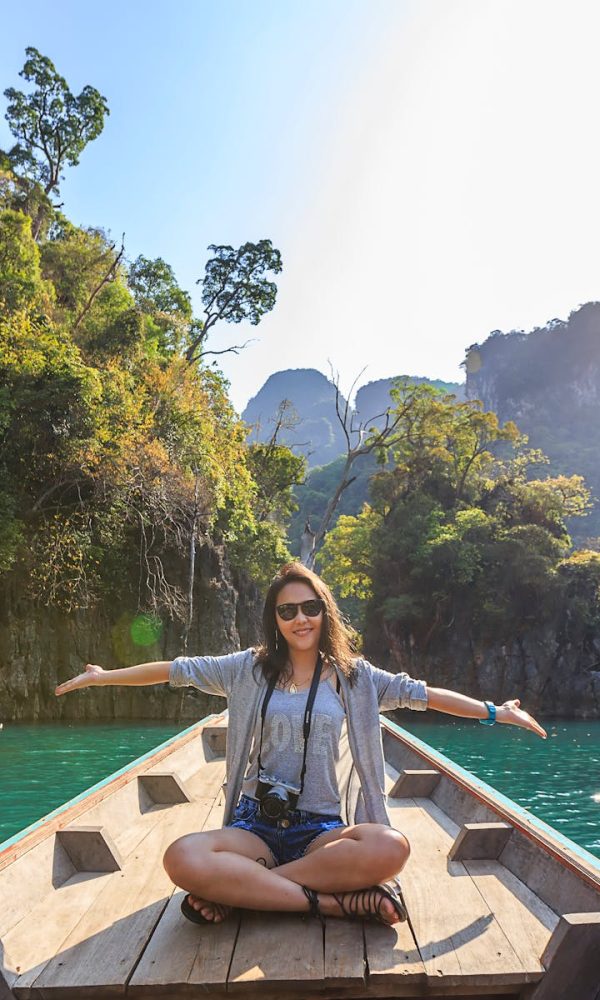 Asian woman relishing a serene boat journey through the lush karst landscape of Thailand's Khlong Sok.